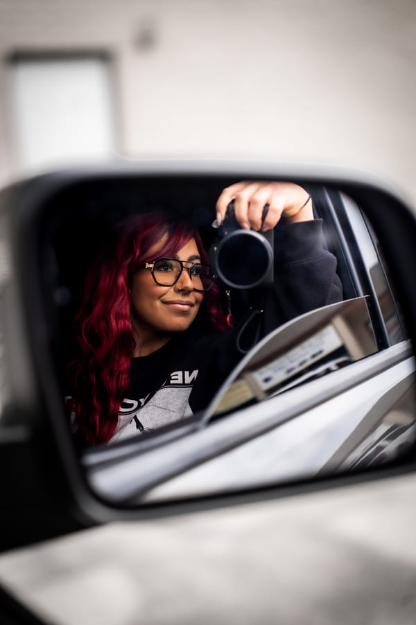 Brooklyn Sanchez reflected in a car mirror with her camera