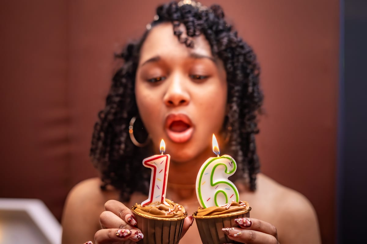 Teen blowing out number 16 candles on a pair of cupcakes