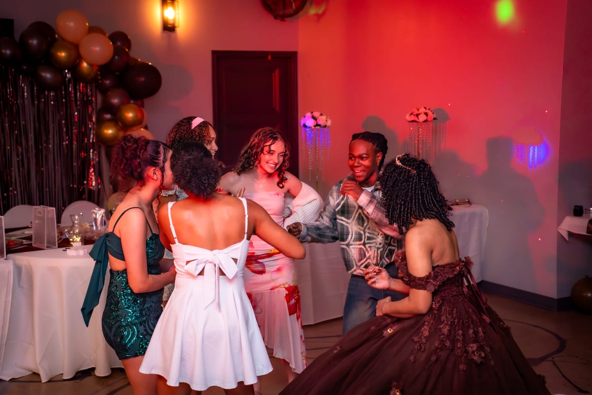 Guests dancing under red party lights at a sweet sixteen