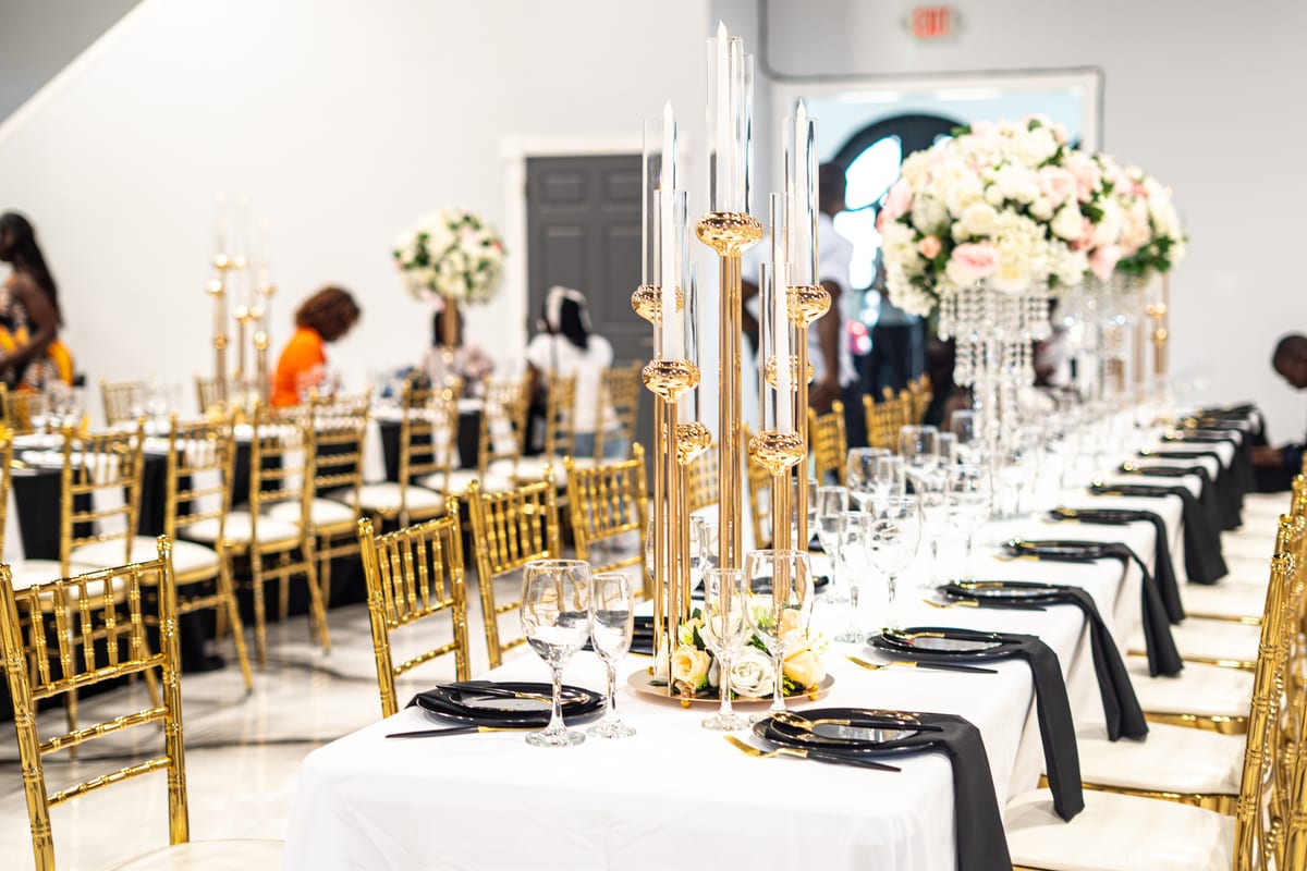 Long banquet table with gold candelabras and floral arrangements as guests arrive