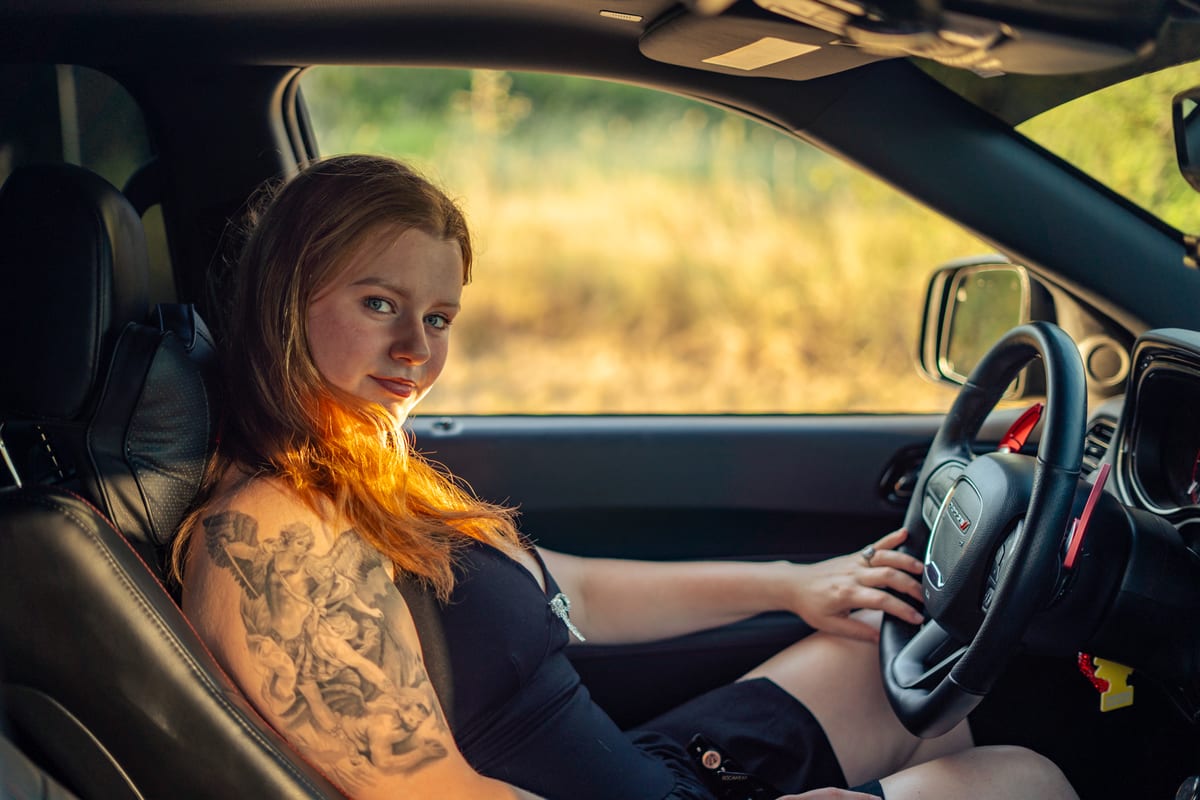 Woman with a sleeve tattoo sitting behind the wheel of a pickup truck