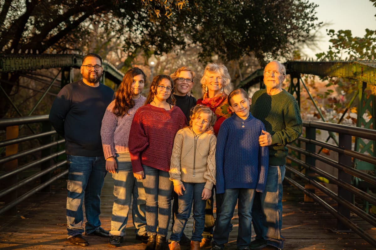Extended family in matching striped jeans standing together on a footbridge