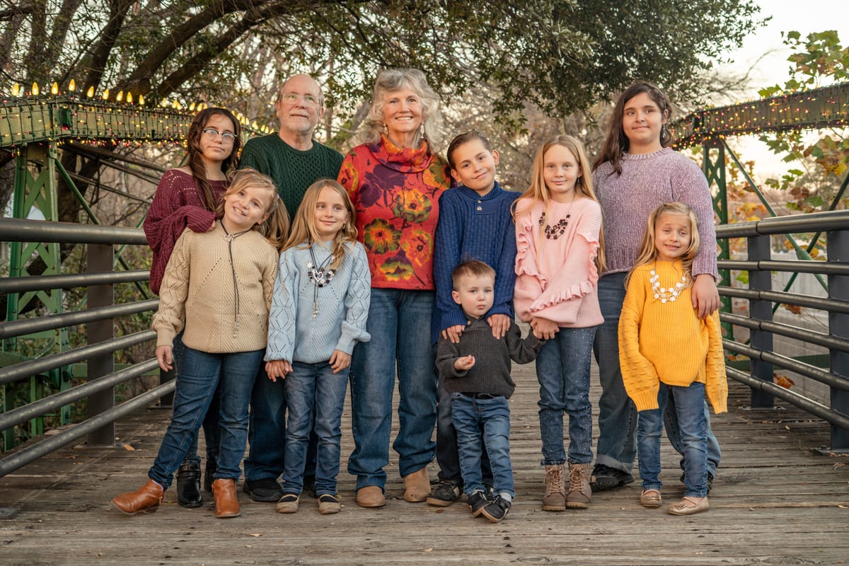 Three generations of an extended family posed together on a footbridge